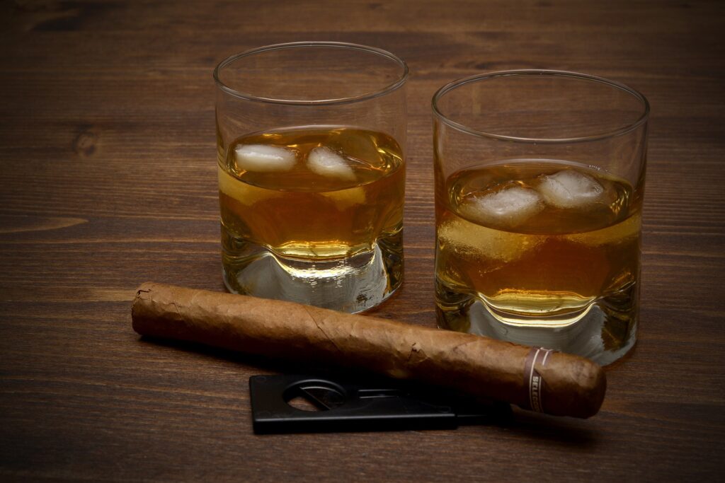 Due bicchieri con whiskey e ghiaccio e un sigaro